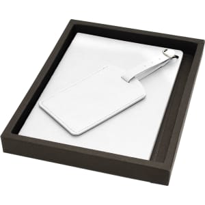 A white leather luggage tag and soft cover journal set in a black presentation box.