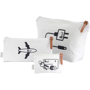 A set of three cream-coloured canvas bags with black designs, featuring an airplane, charger symbol, and key motif.