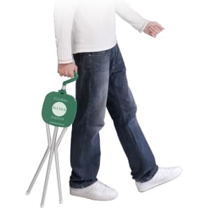 A green folding chair being carried by a person in jeans and white shoes, featuring a logo on the backrest.