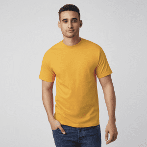 A man wearing a bright yellow unisex heavyweight cotton t-shirt, paired with blue jeans, standing against a plain background.