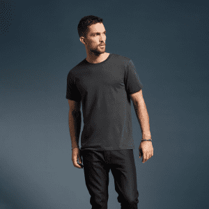 A dark grey adult T-shirt with a classic cut, featured on a model against a solid background. The shirt has a logo.
