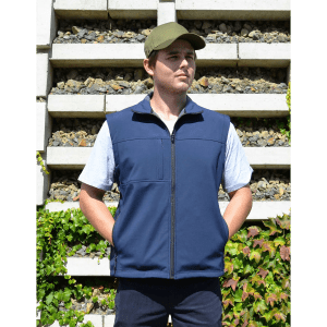 A navy blue softshell vest on a model, featuring a zip front and pockets, paired with a green cap.