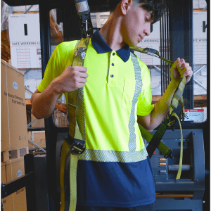A reflective hi-vis yellow and navy short sleeve polo shirt with a pocket and a logo, worn by a model in a warehouse.