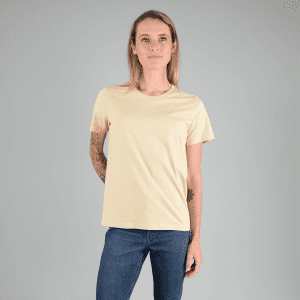 A light yellow ladies' T-shirt with a relaxed fit, paired with blue jeans. The shirt features a logo.