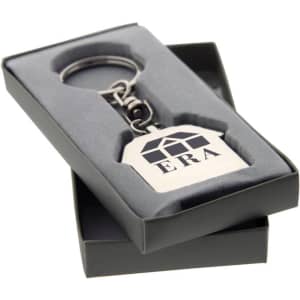 A silver keychain in the shape of a house, presented in a grey box with a logo.