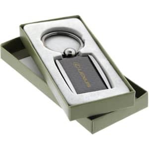 A carbon fibre keychain in a gift box with a metallic keyring and a logo. The box is green and the keychain is dark.