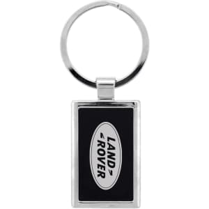 A silver keychain with a rectangular design featuring a black background and a logo.