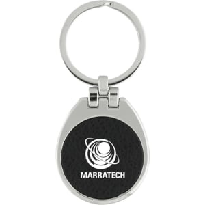 A keychain with a silver metallic finish and a black textured circular centre featuring a logo.