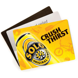 A vibrant counter mat featuring a yellow design with branding and images related to a drink, layered on dark and light mats.