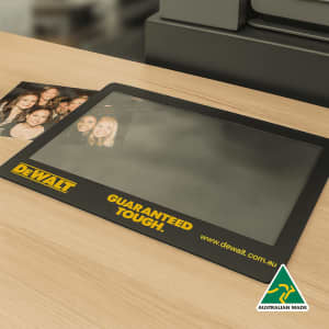A black framed insert counter mat featuring a smooth surface, with a logo and a photo.