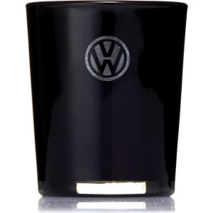 A glass candle in a sleek black holder with a logo on the front. The candle features a gold base.