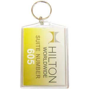 A hotel keychain with a transparent plastic casing, featuring yellow and white colours and a logo.