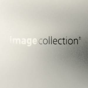 A sleek, metallic silver business card holder features a subtle logo and a refined, glossy finish.