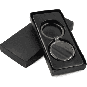 A gunmetal keychain presented in a black gift box, featuring a sleek, circular design.