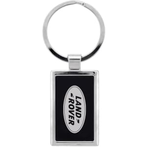 A silver keychain featuring a rectangular design with a black background and a logo.