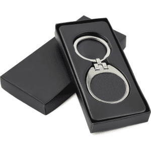 A black leather keychain with a silver metal frame, presented in a sleek black box.