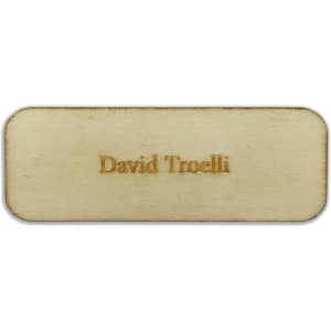 A rectangular wooden badge in light tan with a name engraved on the surface, featuring a subtle, polished finish.