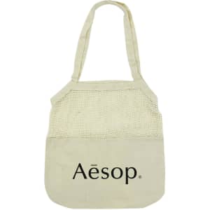 A light beige cotton shopping tote with a mesh top section and a logo on the front.