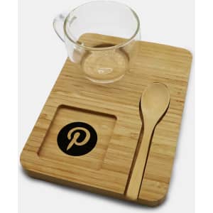 A glass cup, bamboo tray, and wooden spoon, featuring a logo on the tray. Natural tones dominate the set.