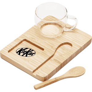 A clear glass cup sits on a bamboo tray with a wooden spoon, featuring a logo on the tray.