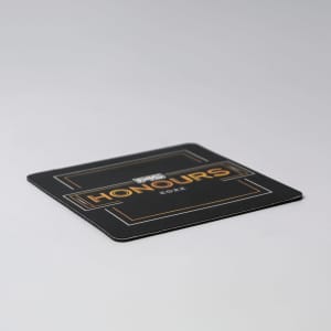 A black deluxe coaster featuring gold accents and a logo, with the word "Honours" prominently displayed.
