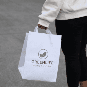 A white insulated reusable bag with two handles, featuring a logo on the front.