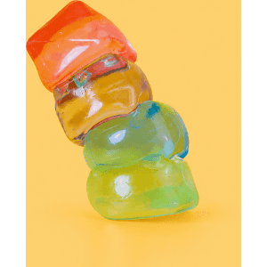 A vibrant stack of jelly cube sensory toys in red, orange, yellow, and green against a bright yellow background.