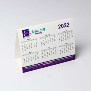 A desk calendar featuring months from January to June 2022, with a white background and purple accents. It includes a logo.