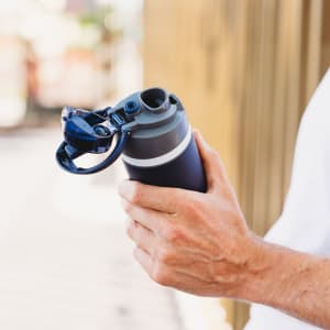 A drink bottle in navy blue with a grey lid and a built-in straw, featuring a logo on the side.