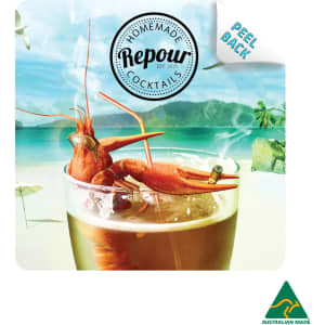A colourful cocktail with a shrimp garnish rests on a beach-themed coaster featuring a logo and branding.
