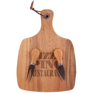 A wooden acacia cheese board in a paddle shape with two cheese knives, featuring a leather hanging loop.