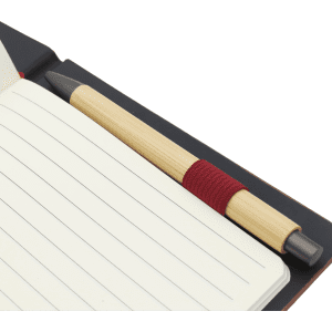 A dark notebook with lined pages and a bamboo pen with a red grip placed inside.
