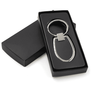 A sleek silver keychain with an oval design, presented in a black box.