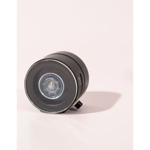 A black vacuum suction magnetic phone stand with a glossy finish and a circular shape, featuring a small control knob.