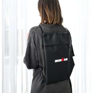 A black drawstring bag with a logo, worn on the back of a person, featuring a sleek design.