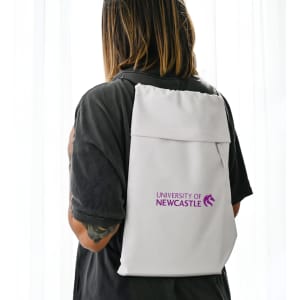 A white drawstring bag is worn on the back, featuring a logo. The bag has a minimalist design with a sleek appearance.
