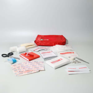 A red first aid kit containing bandages, gauze, antiseptic wipes, scissors, and a first aid manual.