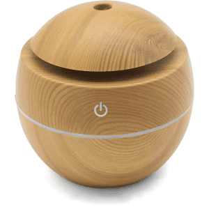 A round wooden diffuser in a light timber finish with a circular design and a power button.