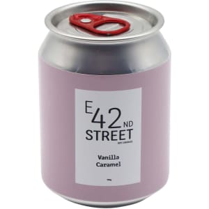 A pink can-shaped candle with a silver lid, featuring a label for 'Vanilla Caramel' fragrance and a logo.