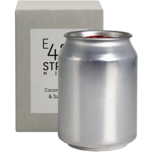 A silver can candle sits beside a square grey box, showcasing a sleek design and minimal branding.