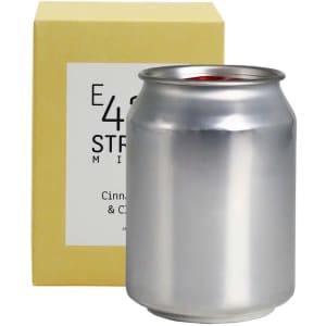 A silver can candle packaged in a yellow box, featuring a simple logo on the can.