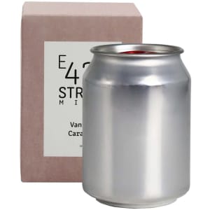 A silver can candle beside a light pink box, featuring a logo on the packaging.