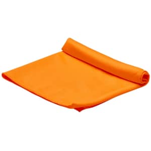 An orange cooling towel is neatly rolled up, featuring a textured surface. It has a logo on one side.