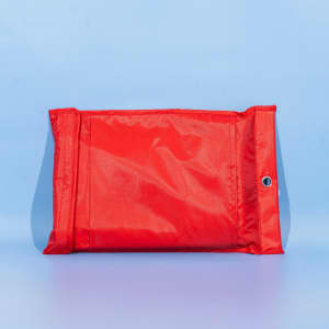 A red fiberglass emergency fire blanket in a protective pouch, featuring a metallic eyelet for hanging.
