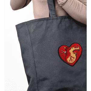 A large black tote bag featuring a heart design, with an embroidered graphic in red and gold tones.
