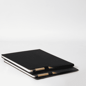 A black A4 notebook stacked with a pen, featuring a simple design and a logo on the cover.