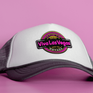 A grey and white cap featuring a round logo with vibrant pink and black elements.