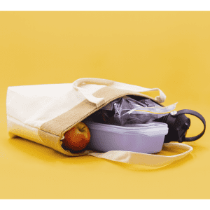 A jute and cotton cooler bag with a drink bottle, a food container, and an apple inside, featuring a neutral colour scheme.