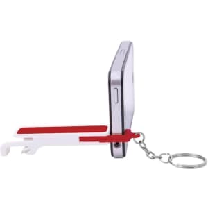 A drink bottle opener in red and white, attached to a keychain and resting against a smartphone.