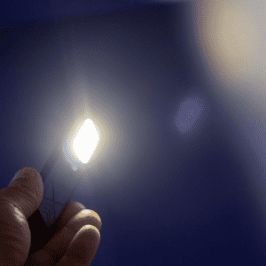 A handheld rechargeable work light emits a bright white light against a blue background. It features a logo on its surface.